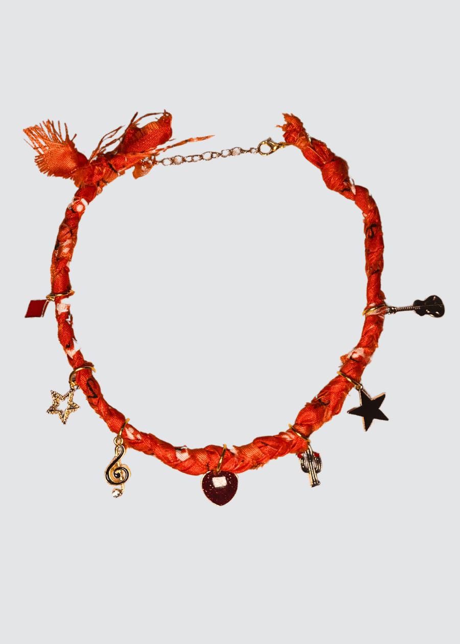 handgemacht orangefarbene Bandana Kette mit Fransen und auffälligen Charms auf hellen Hintergrund 
